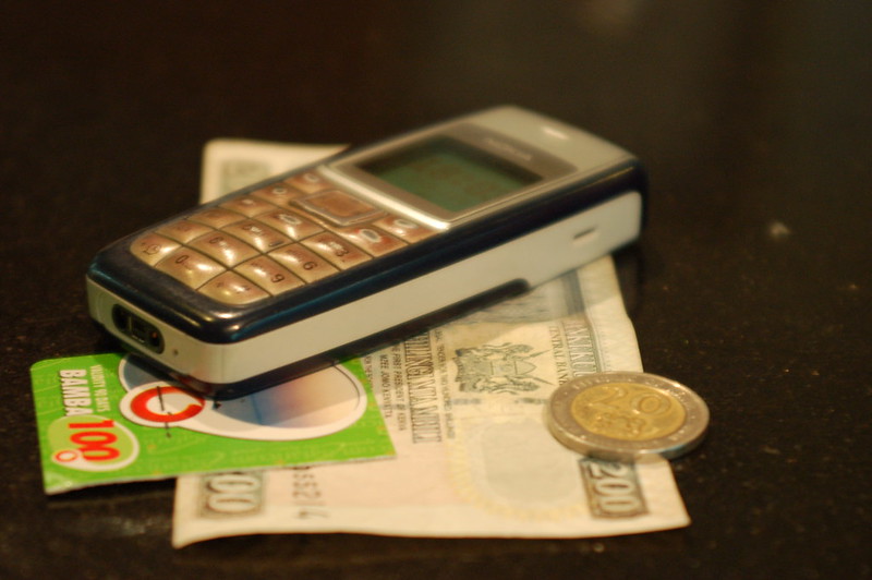mobile phone money - Erik (HASH) Hersman Mobile Phone with Money in Kenya - CC BY 2.0